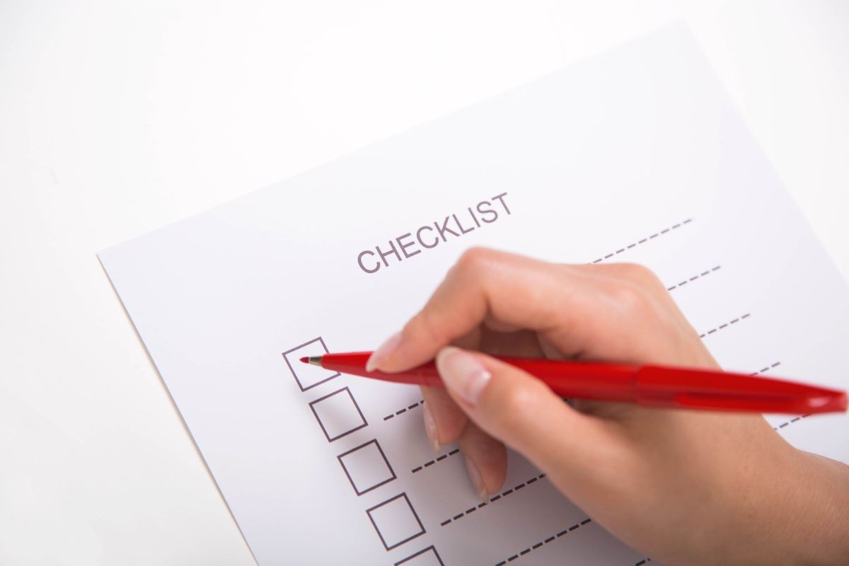Close-up of hand marking on checklist with red pen Close-up of hand marking on checklist with red pen